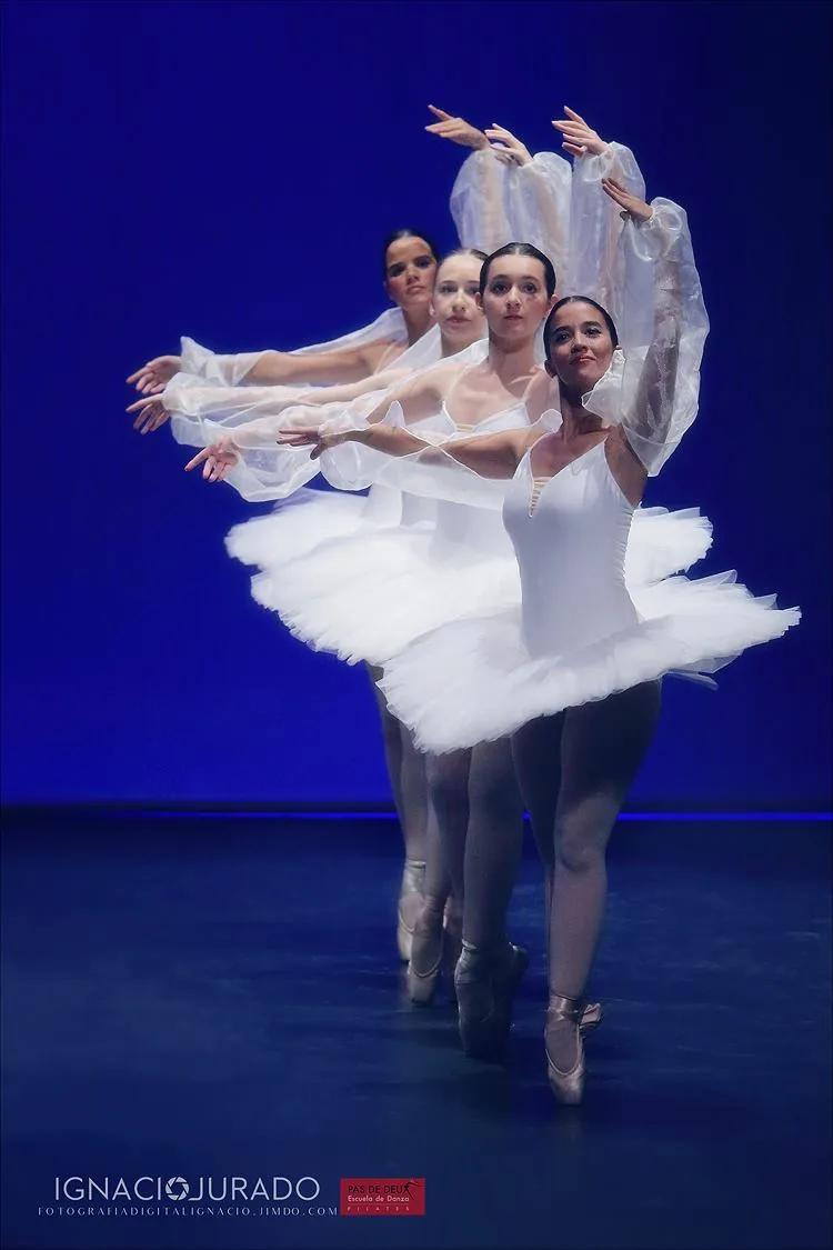 Cuatro bailarinas de la escuela con tutú blanco sobre el escenario