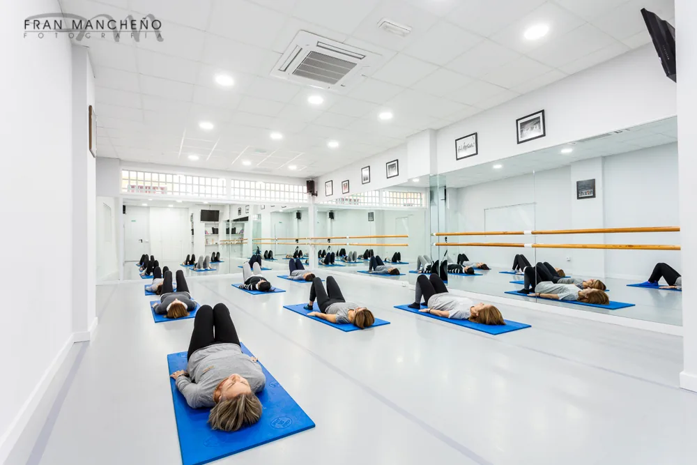 Interior de una de las salas de la escuela, con barras, espejos y suelo profesional de danza