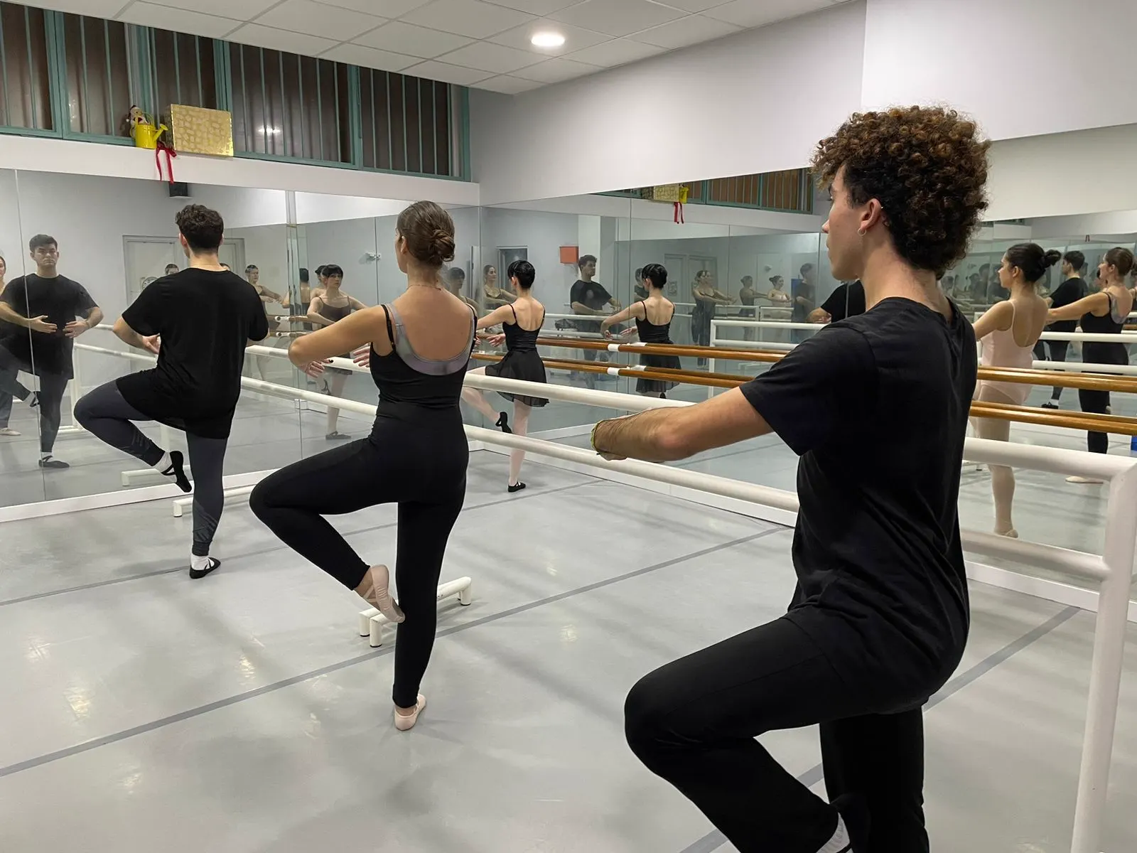 Alumnos de ballet clásico en passé durante una clase para adultos